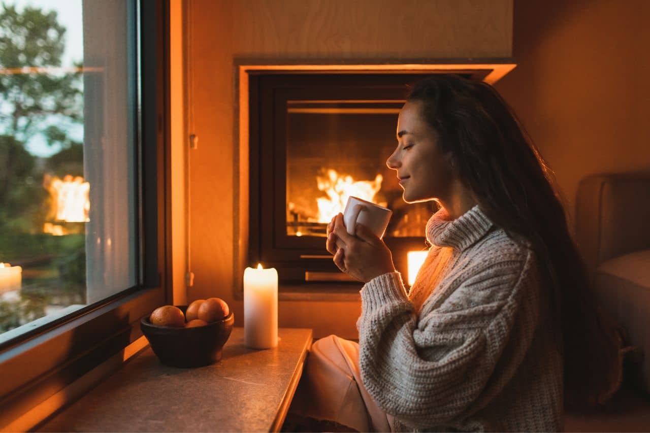 Woman with coffee by a fireplace