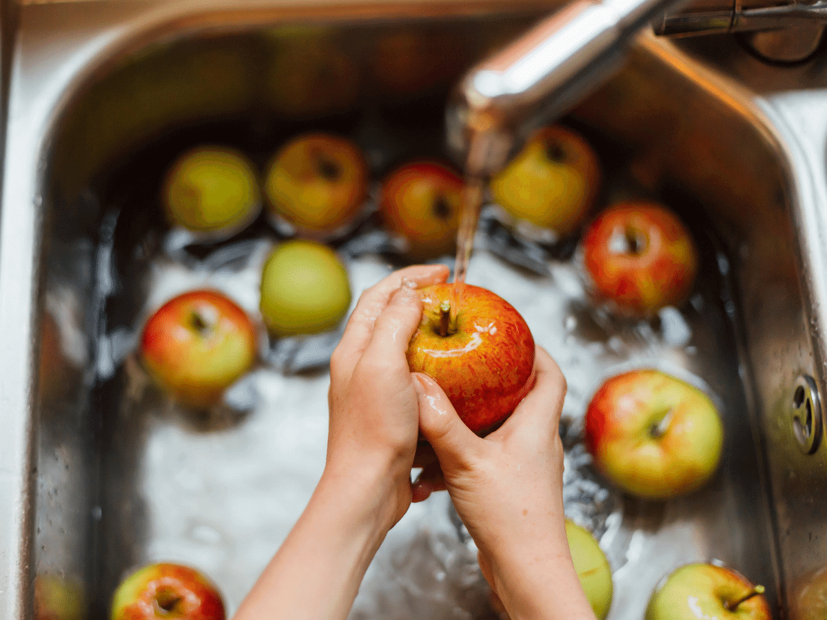 close up of a woman's hands washing apples in the sink
