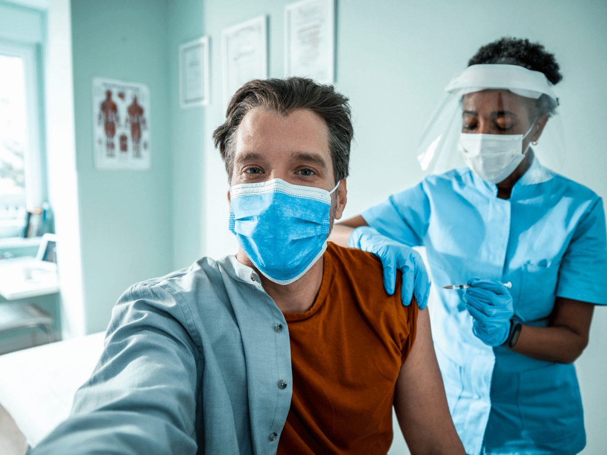 Man takes a selfie as he receives a vaccination.