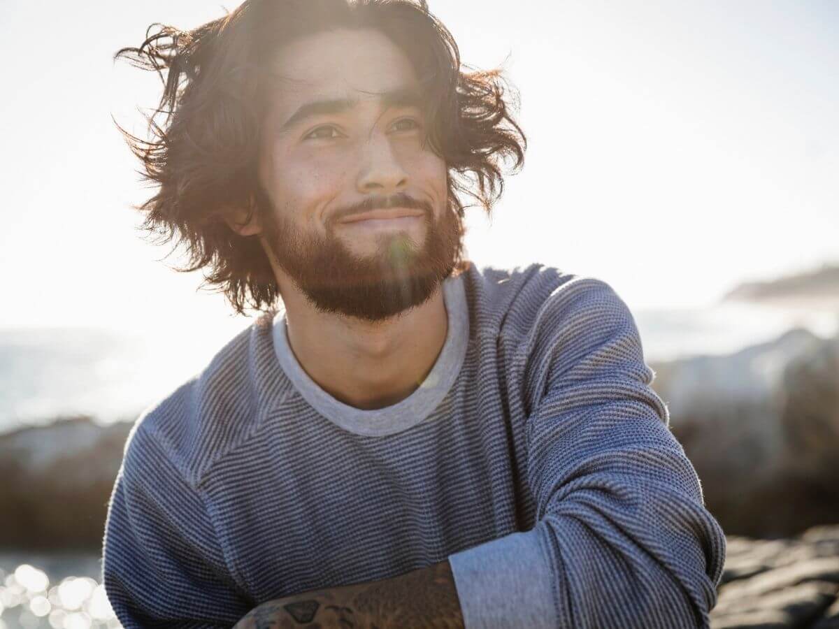 Close up of a man smiling outdoors while the sun shines on him